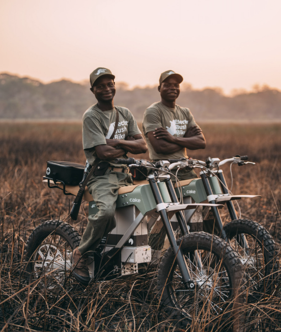 Two riders with CAKE motorcycles in a field